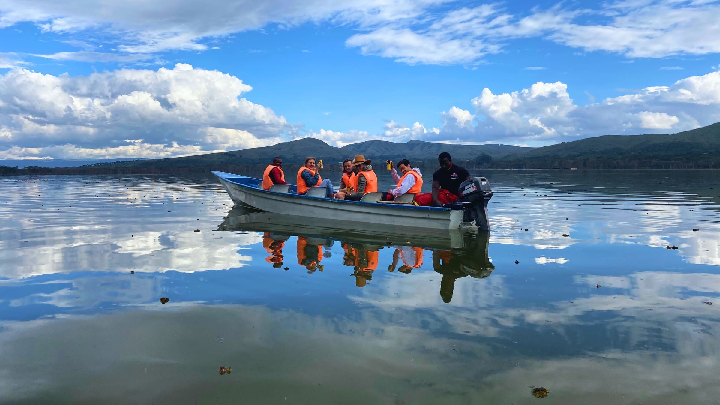Toeristen in een boot met reddingsvesten tijdens een boottocht over het spiegelende water van Lake Naivasha