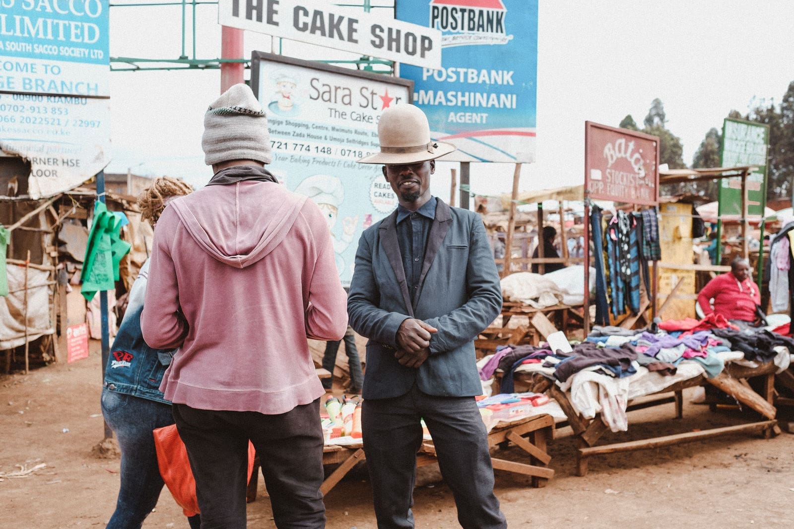 man met opvallende hoed poseert op lokale markt in Kenia