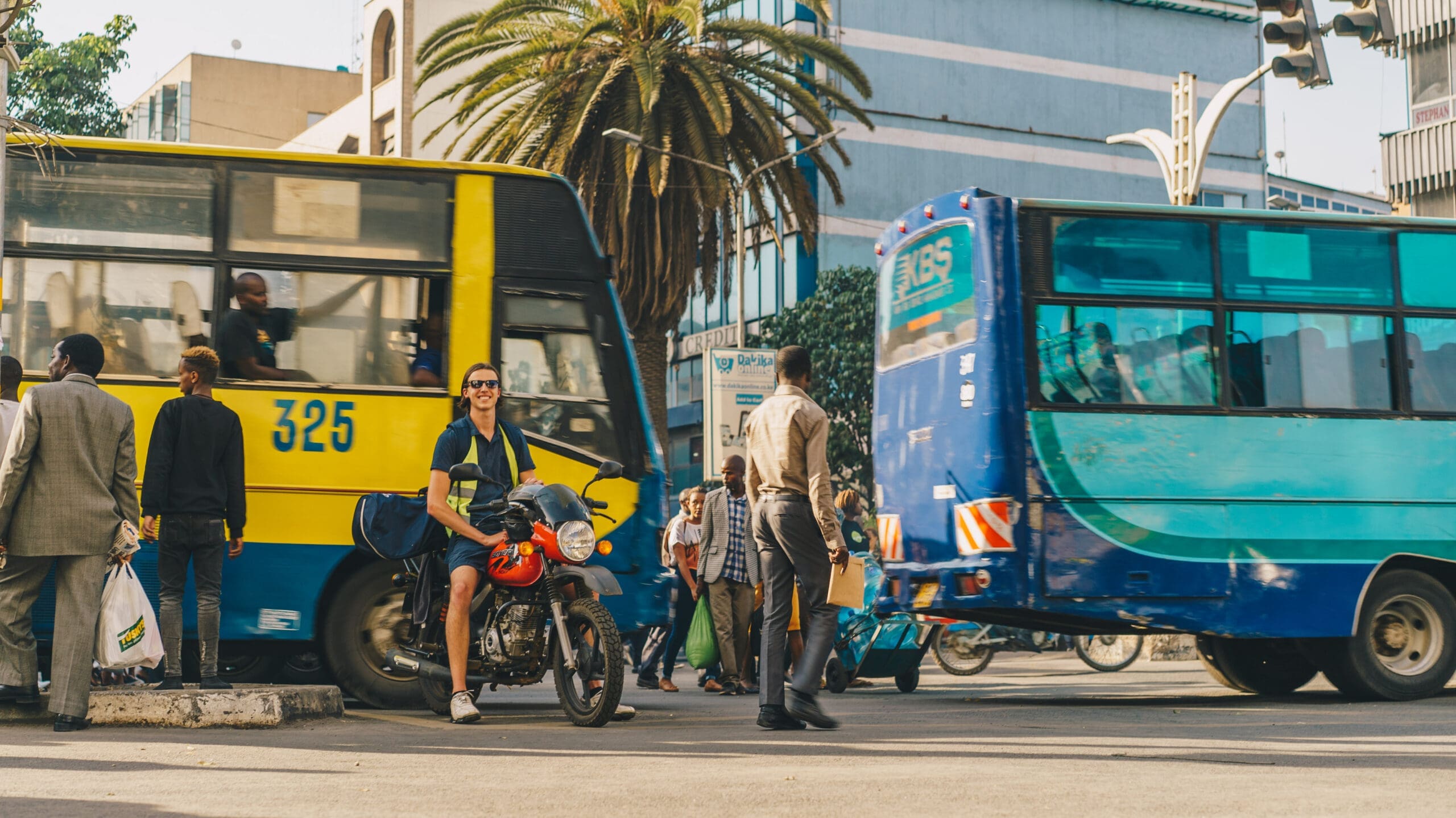 man met motor tussen kleurrijke bussen en druk verkeer in Nairobi centrum
