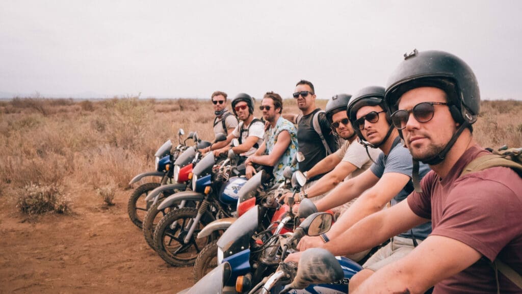 groep mannen met helmen poseren op motoren in droog savannelandschap in kenia