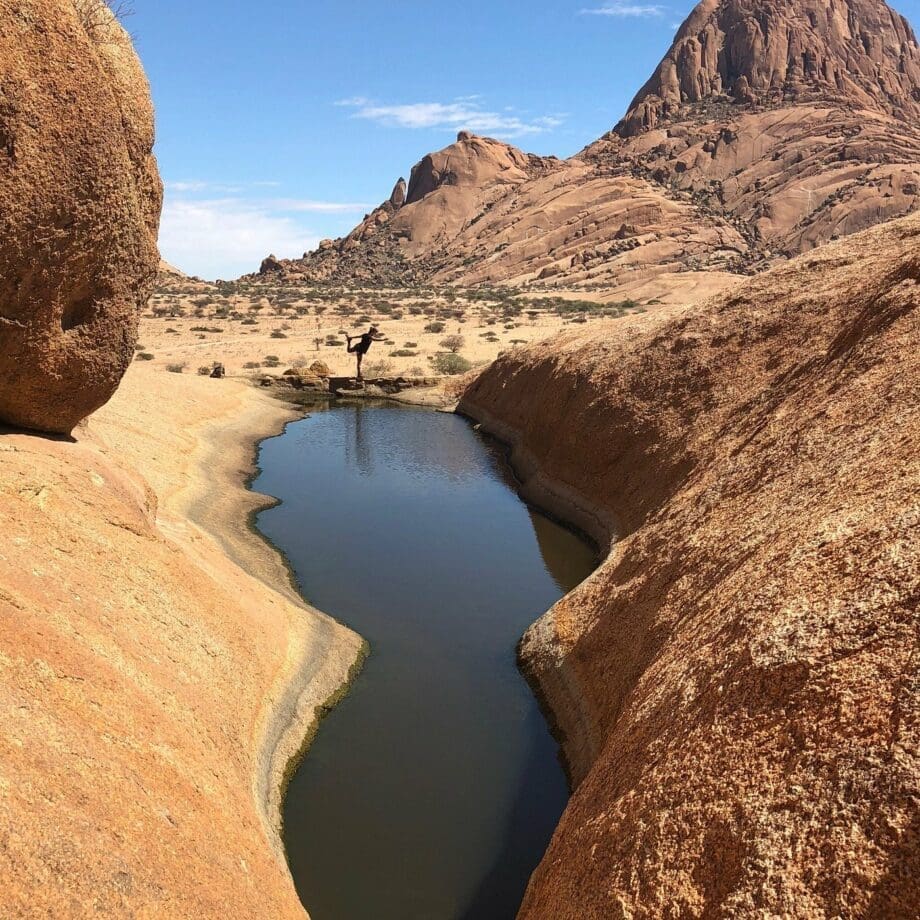reiziger poseert boven rotspoel tussen granieten rotsformaties in de spitzkoppe namibië