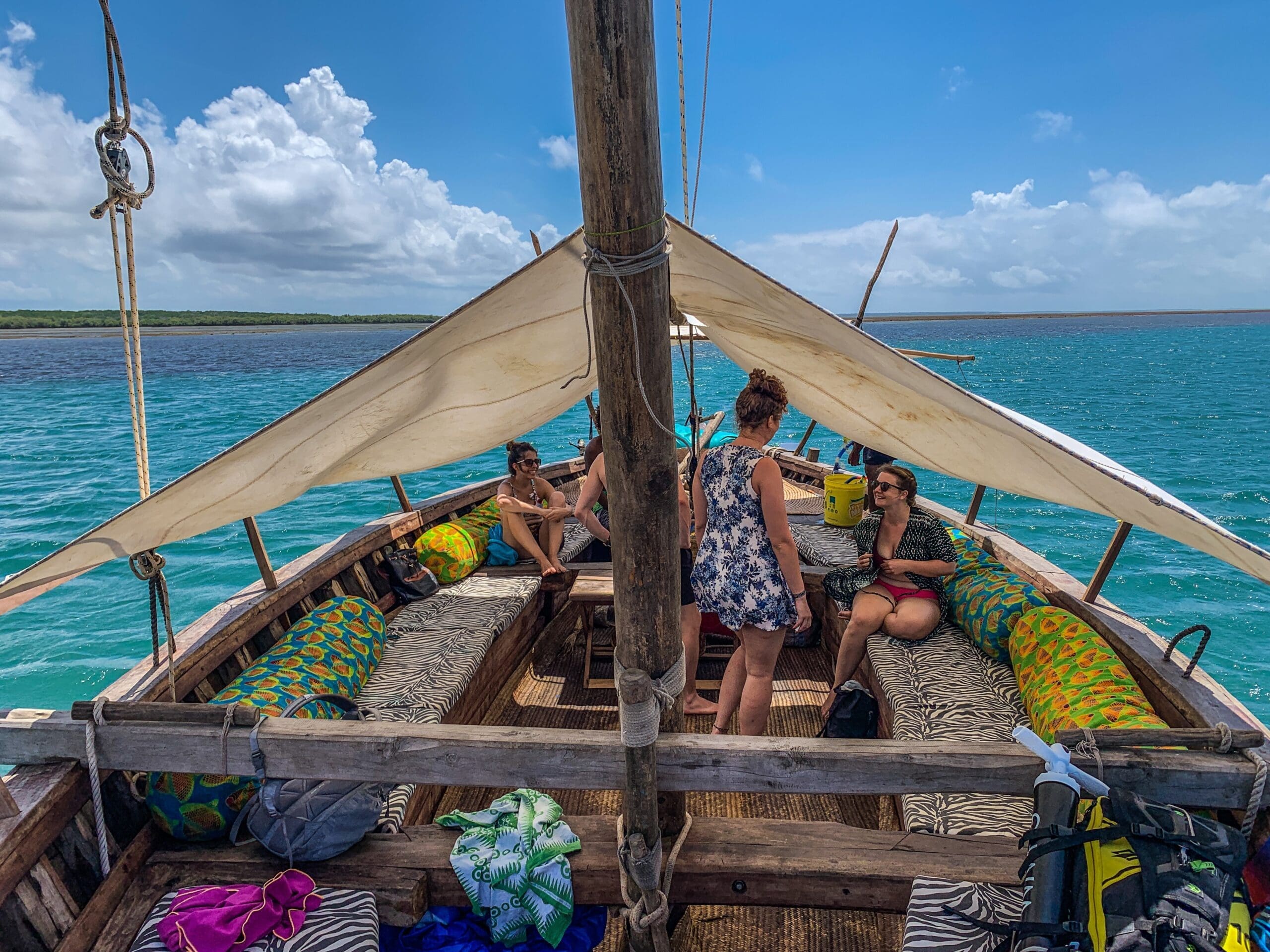 mensen ontspannen op een traditionele houten dhow met kleurrijke kussens op helderblauw water